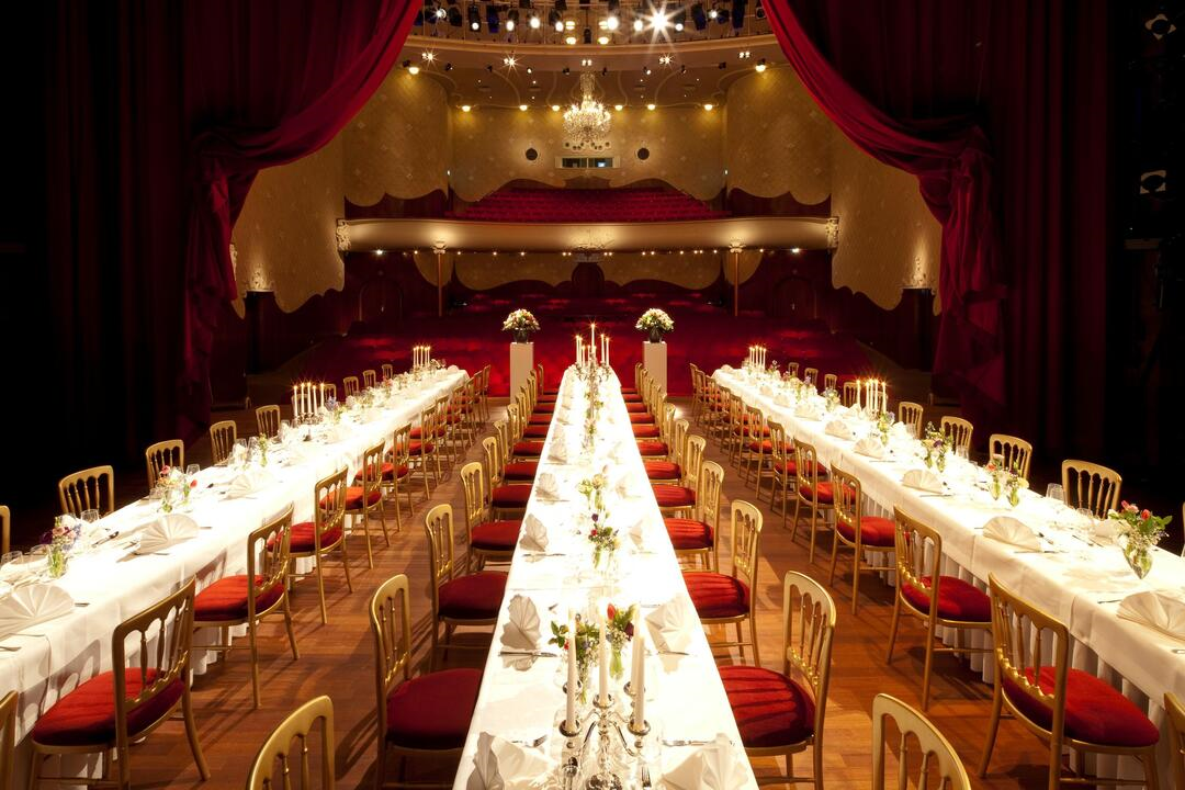 Er staan drie lange tafels die prachtig gedekt zijn op het podium van de grote zaal