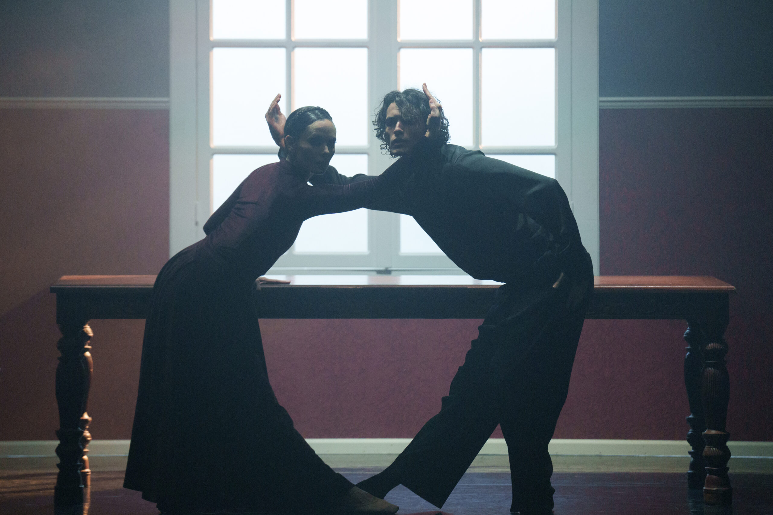 Twee dansers die voor een raam staan en poseren.