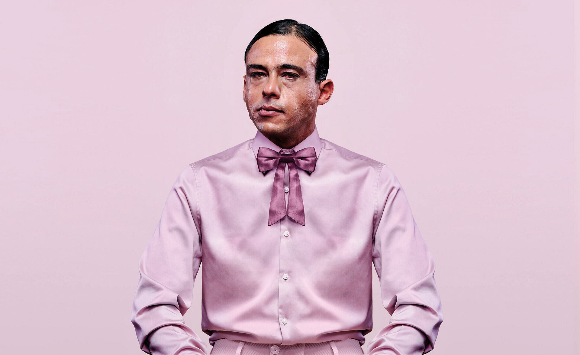 Een man gekleed in roze satijnen kleren die netjes zit