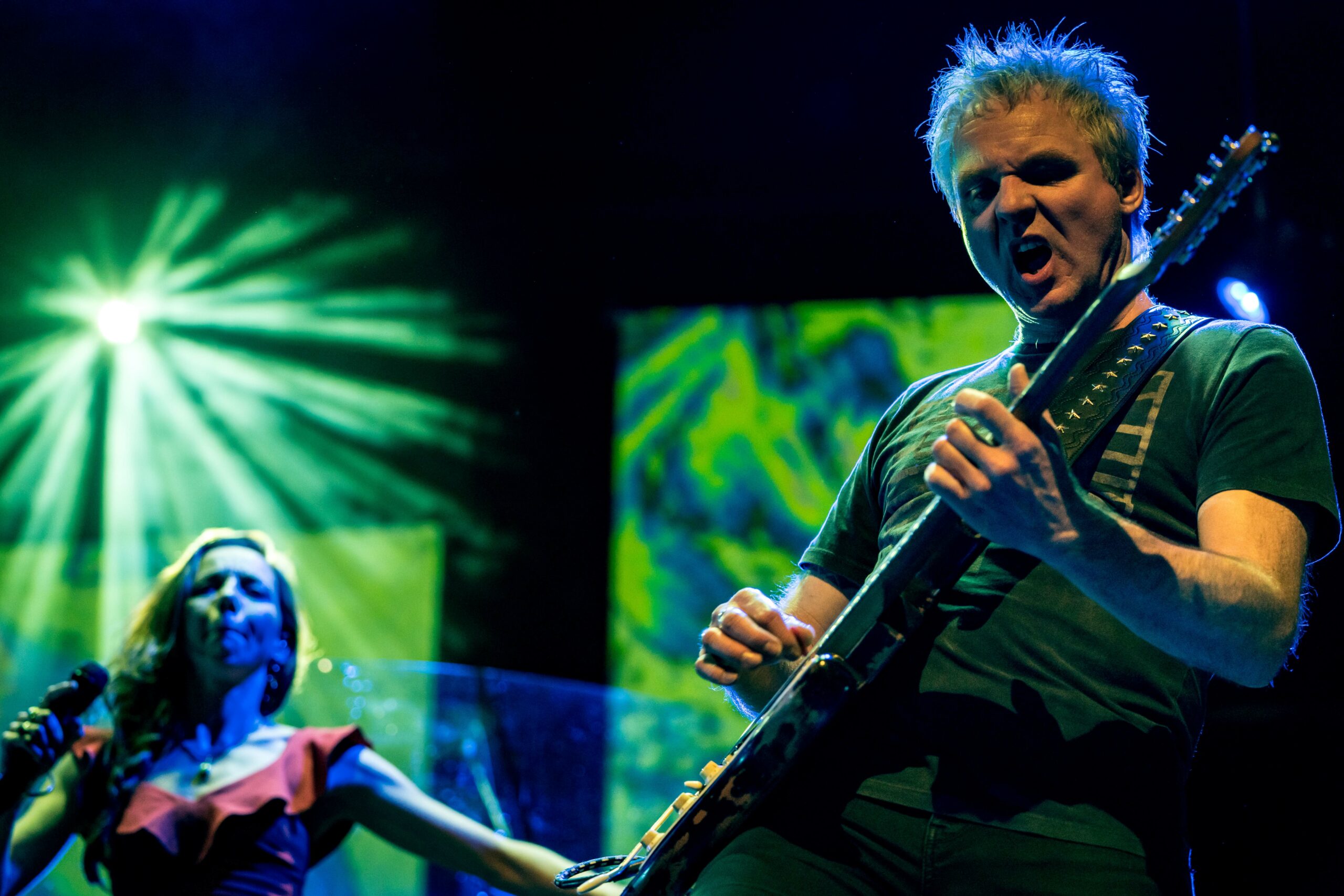 Artiest die op een gitaar speelt en een zangeres die zingt op de achtergrond