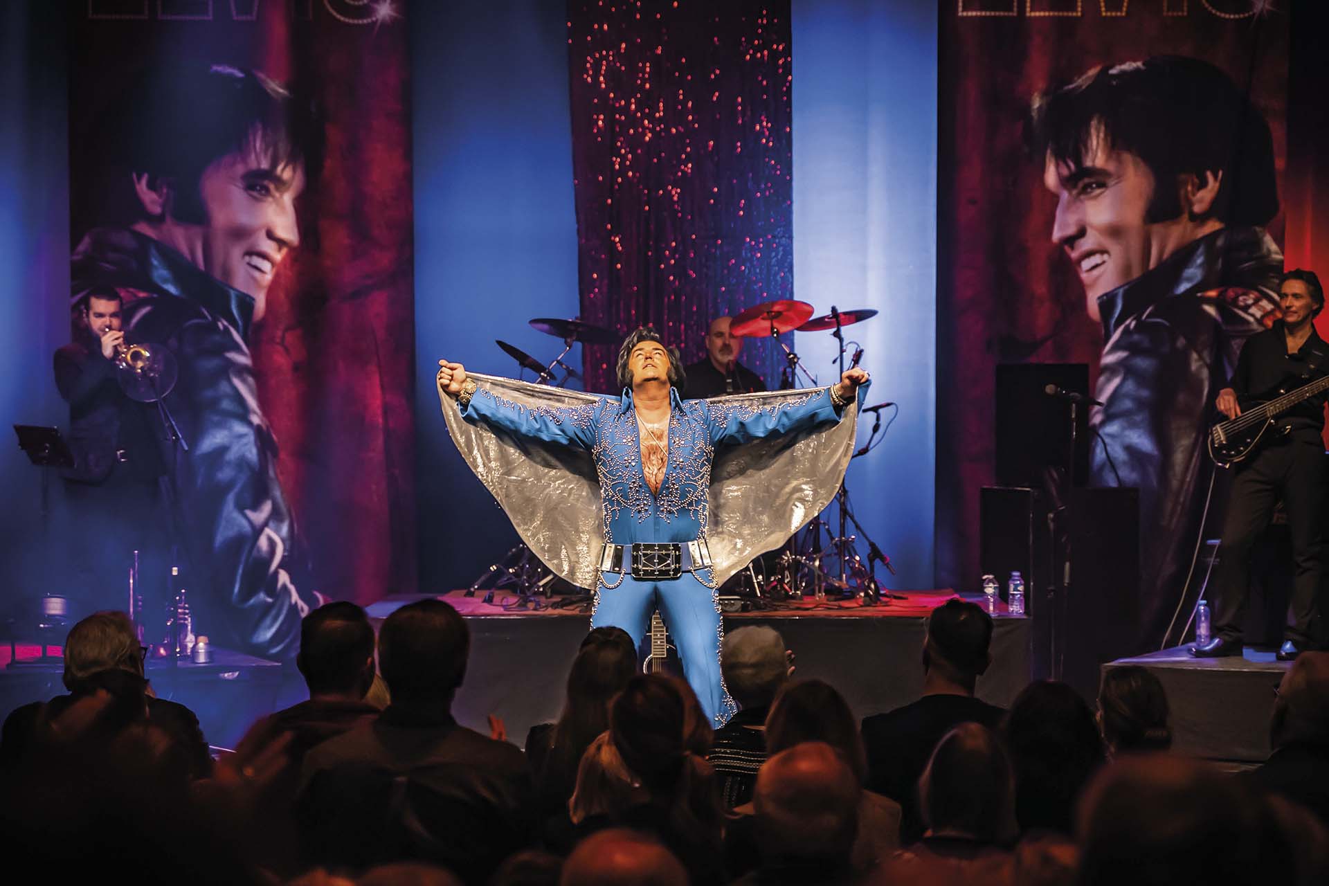 Zanger spreidt armen in iconische Elvis-pose.