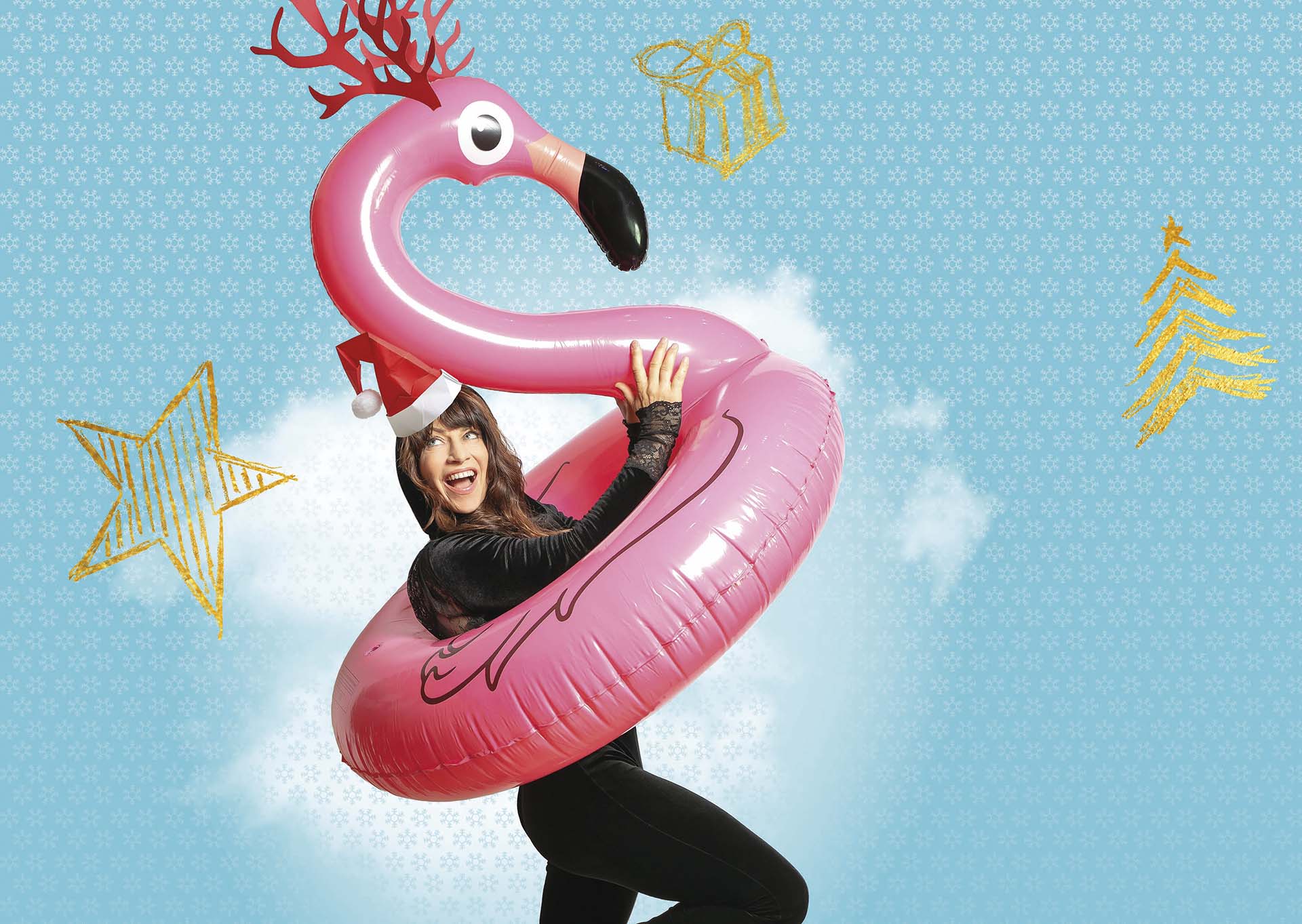 Ellen ten Damme draagt een zwart glitterpak en een roze flamingo-band met kerstmuts en gewei op een blauwe achtergrond vol kerstillustraties.