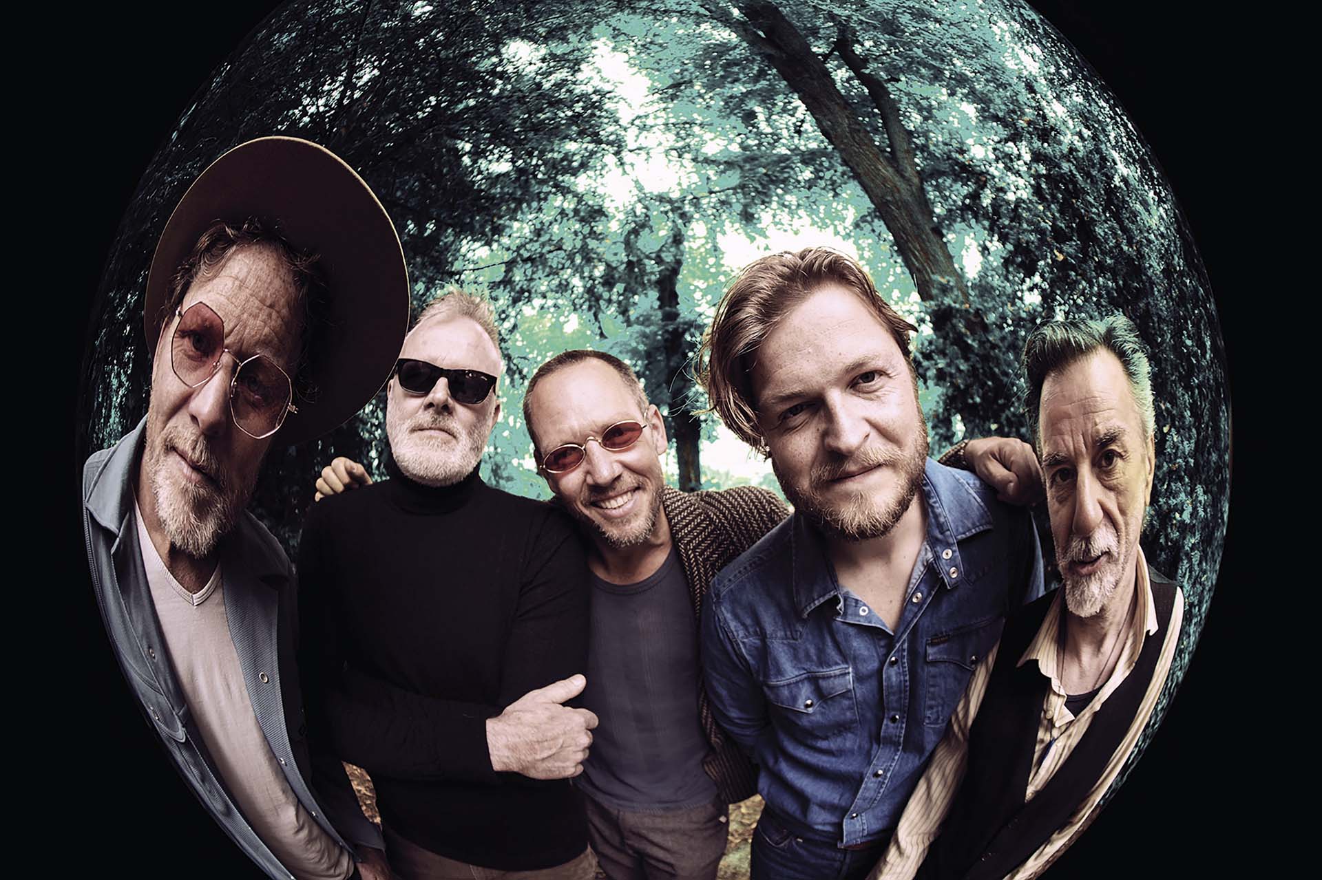 Dezelfde band poseert in een bos, gefotografeerd met een fish-eye lens.