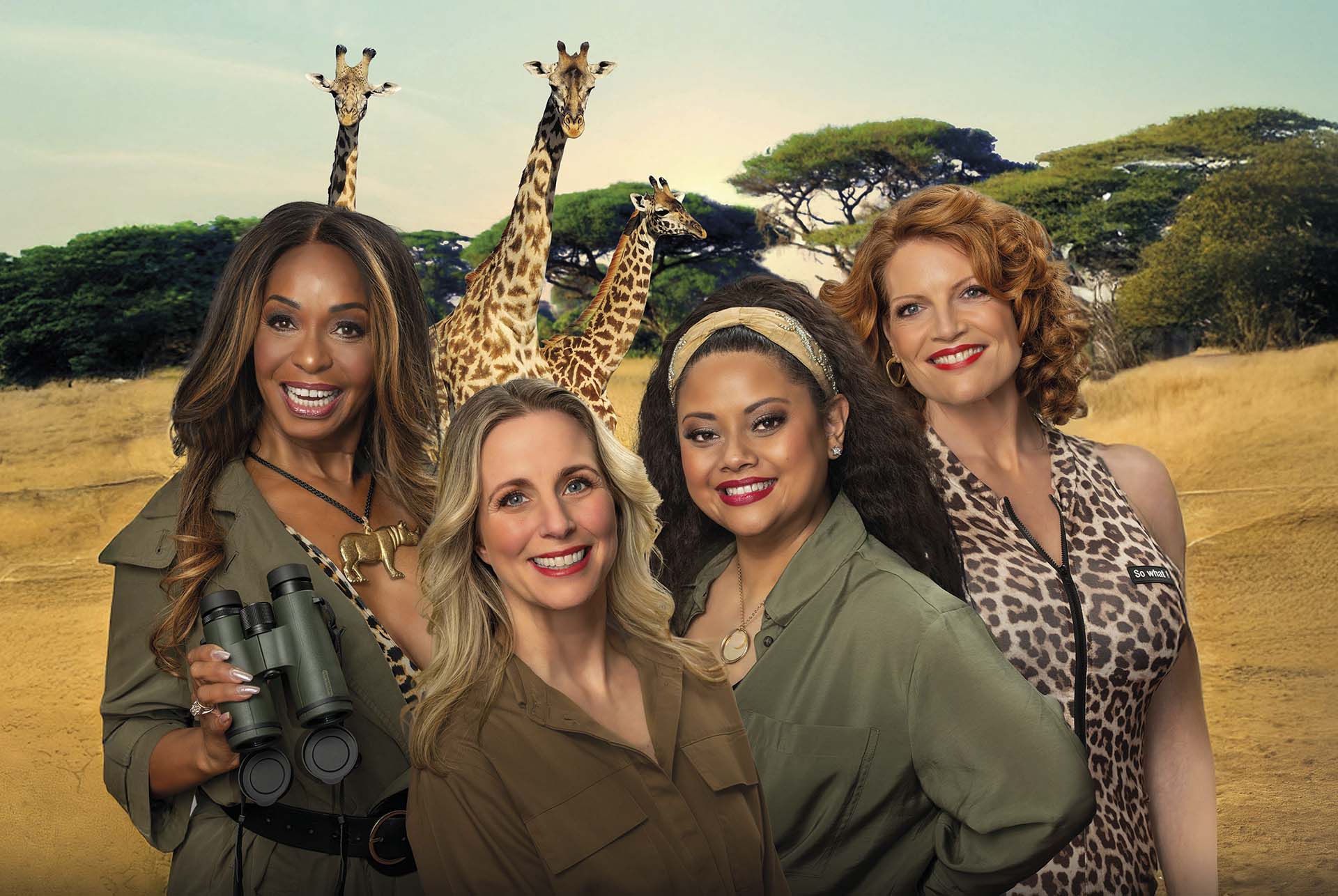 Vier lachende vrouwen in safarikleding poseren voor een Afrikaanse savanne met giraffen op de achtergrond, ter promotie van de voorstelling Opvliegers – Op Safari.