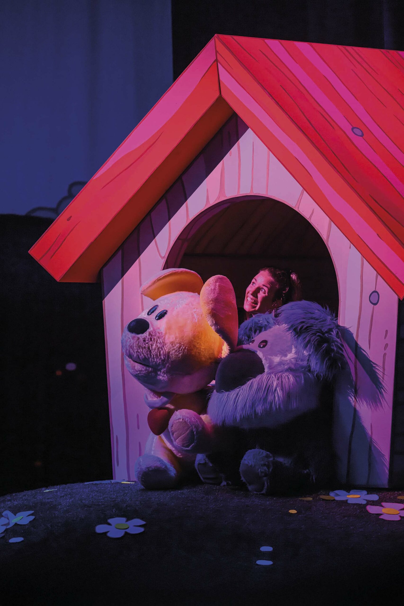 Woezel en Pip kruipen samen in een hondenhok, verlicht door warm theaterlicht.