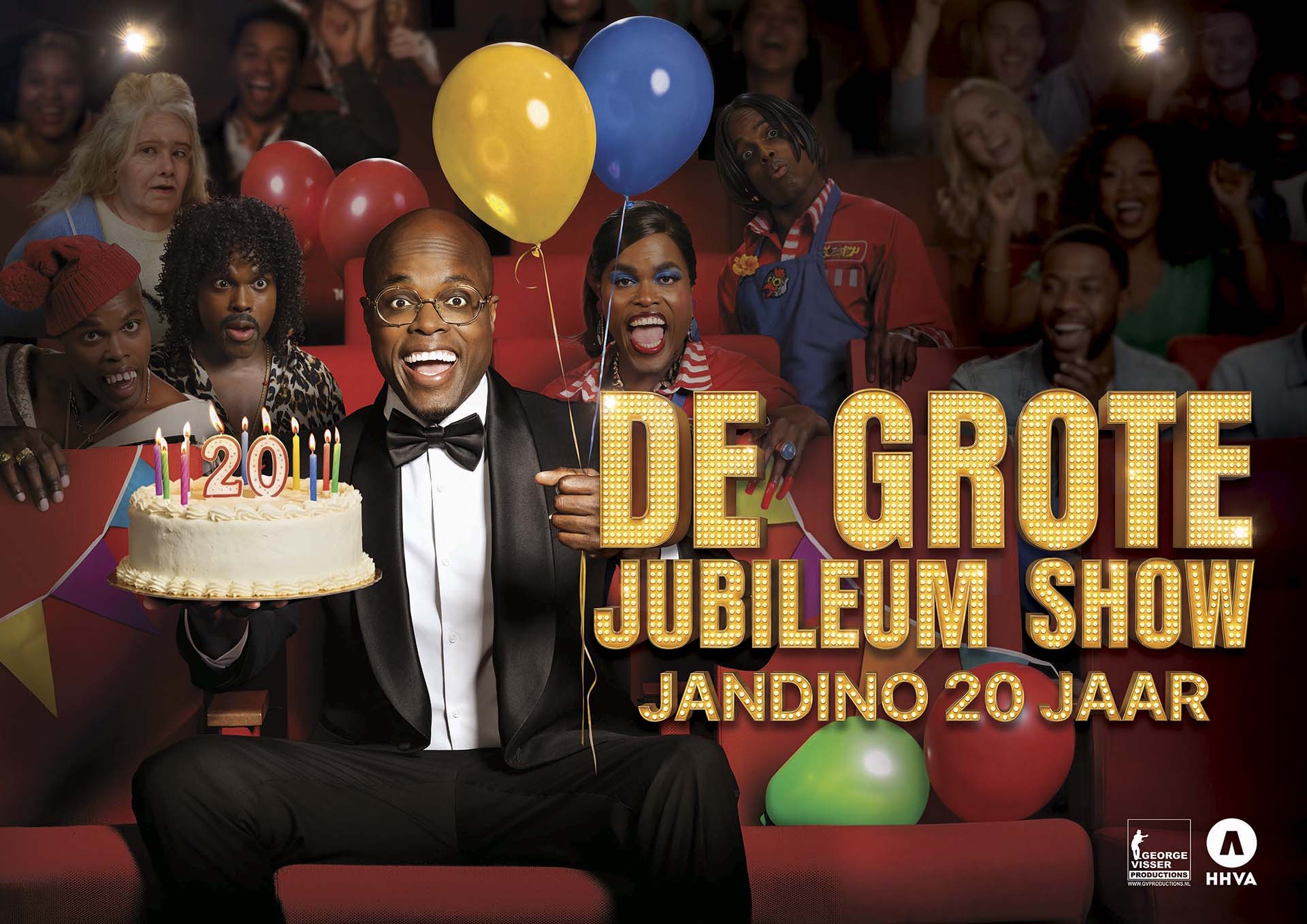 Jandino in smoking houdt taart met kaarsjes vast in theaterzaal vol publiek en ballonnen, promotiebeeld van De Grote Jubileum Show 20 jaar