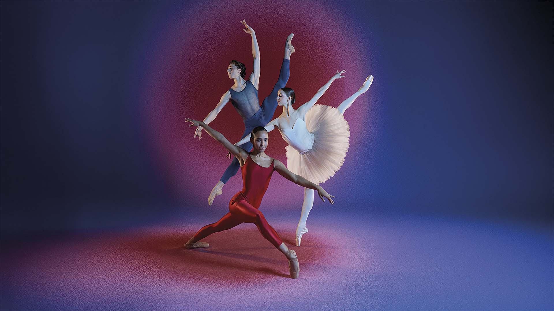 Drie dansers in balletkostuums maken sierlijke sprongen en poses tegen een blauw-roze achtergrond met spotlicht, waarbij kracht en elegantie samenkomen
