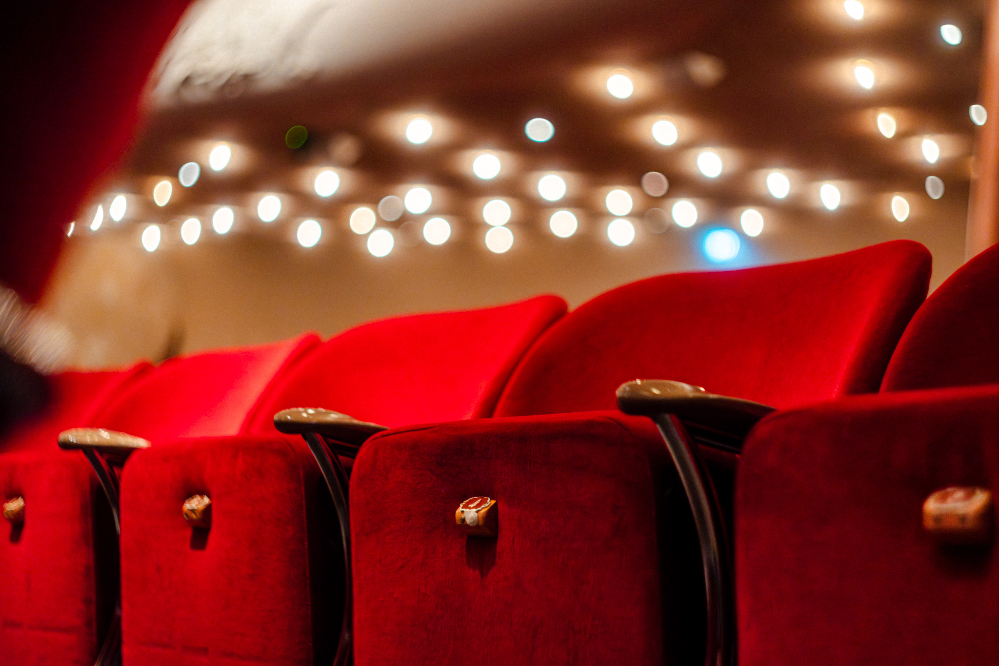 Rode theaterstoelen in een lege zaal met warme sfeerverlichting en lichtjes op de achtergrond