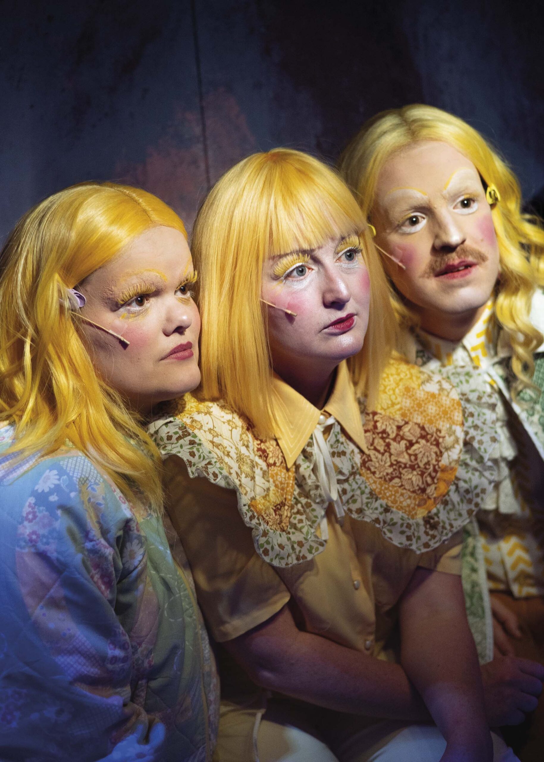 Close-up van drie spelers met blond haar en theatermake-up