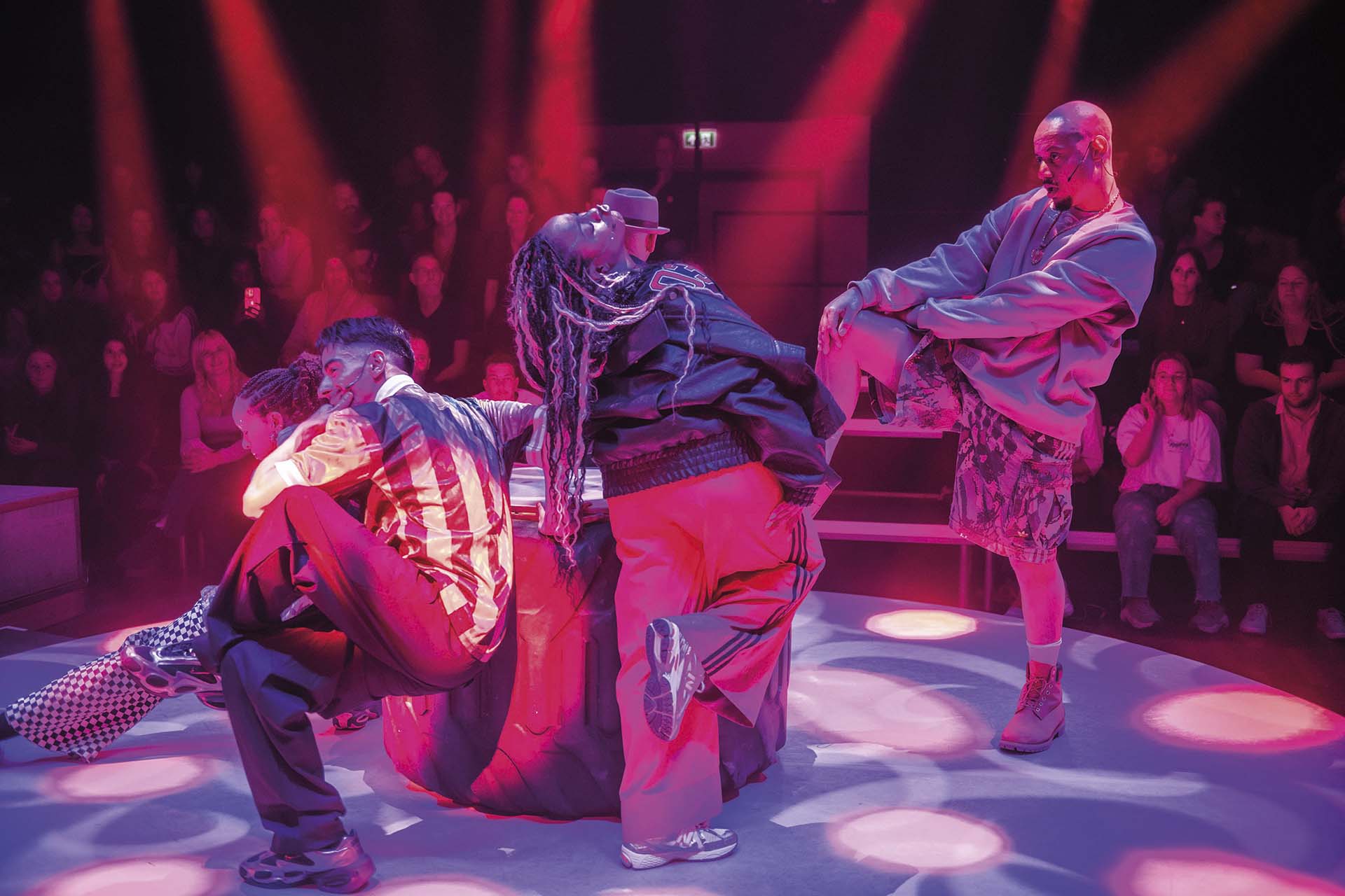 Groep dansers in dynamische pose onder roze licht