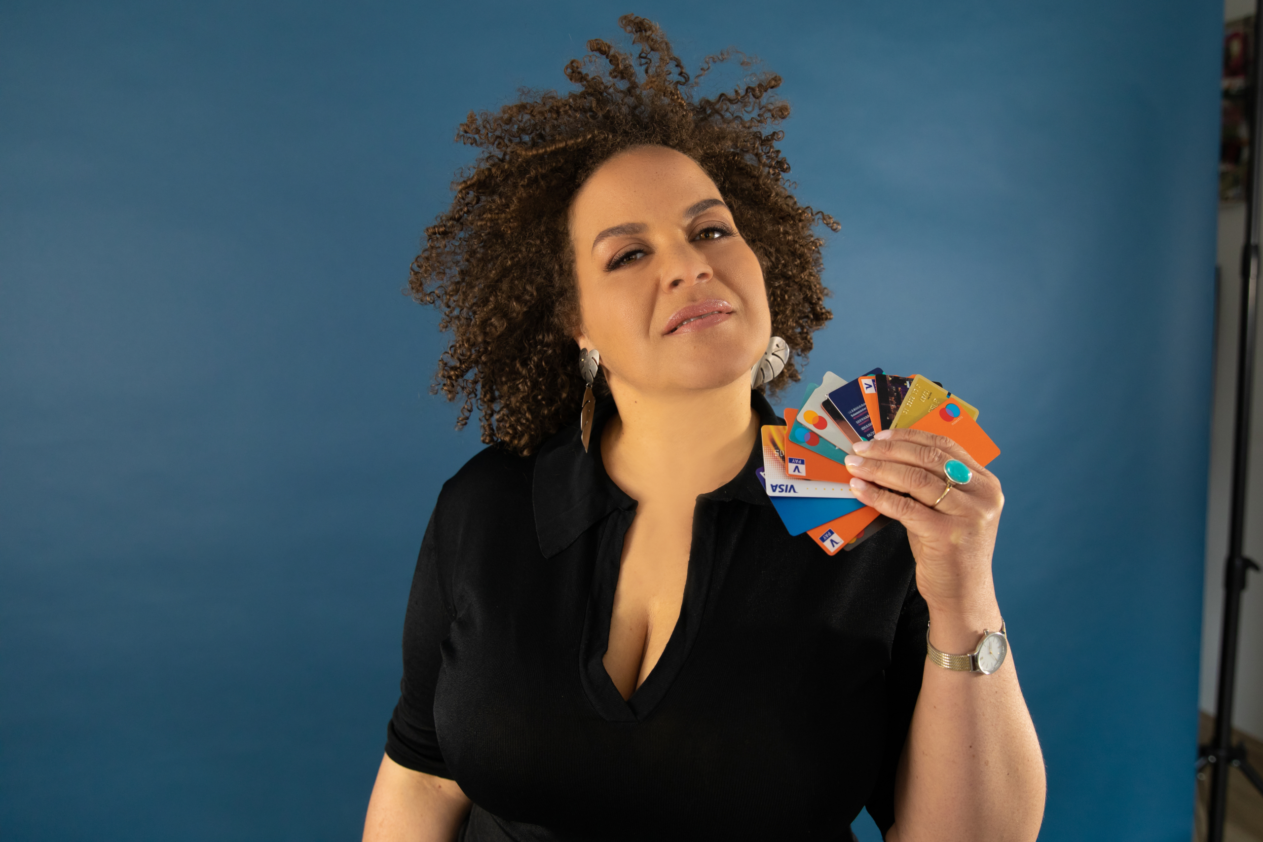 Jeannine la Rose houdt een waaier van bankpassen vast voor een blauwe achtergrond